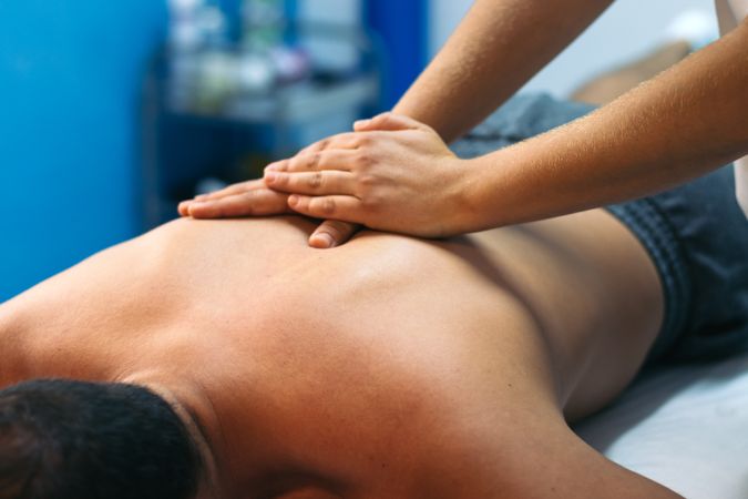 Young woman treating a male patient. back massage physiotherapy. close-up