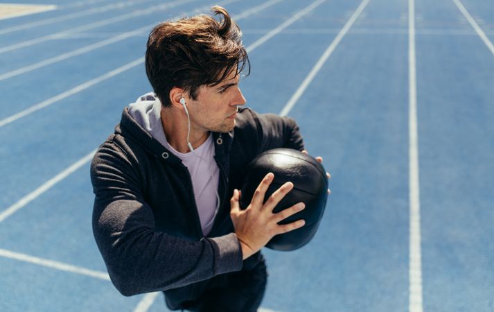 Athlete training with a medicine ball on running track