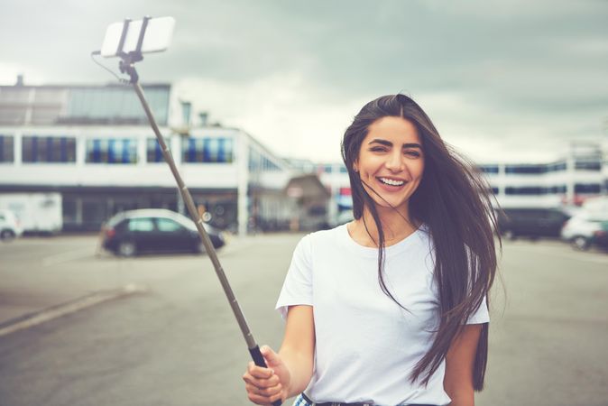 Smiling woman taking selfie in parking lot on overcast day