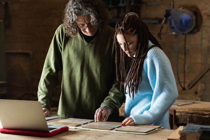 Woman choosing sample with carpenter in workshop