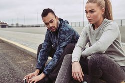 Two people sitting on a curb after running on empty road