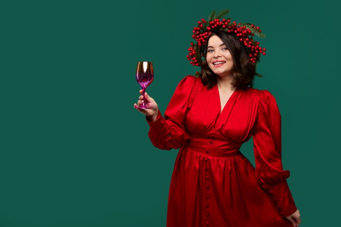 Cheerful woman in red dress holding golden wine glass