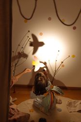 Anonymous girls with raised paper bird creating shadow on wall