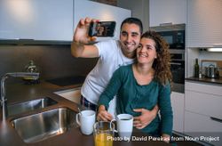 Cute couple in pajamas taking selfie in kitchen at breakfast time bxlWnb