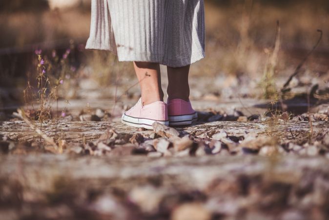 Long haired woman standing on railways overgrown with dry grass