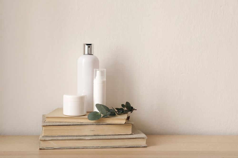 Beauty creams atop pile of books
