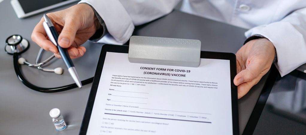 Unrecognizable doctor showing consent form for coronavirus vacci