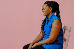 Side view of female with bandage after immunization in pink studio shoot, copy space