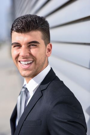 Man in suit next to wall smiling directly at camera