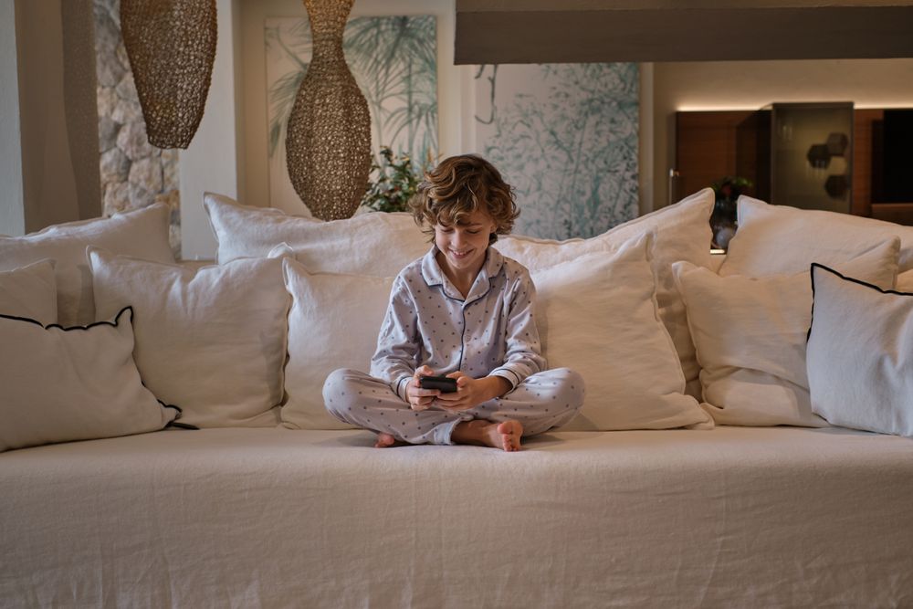 Cheerful boy using smartphone on sofa