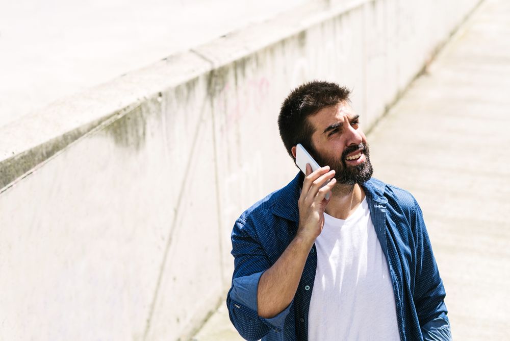 Man in denim walking outside talking on phone