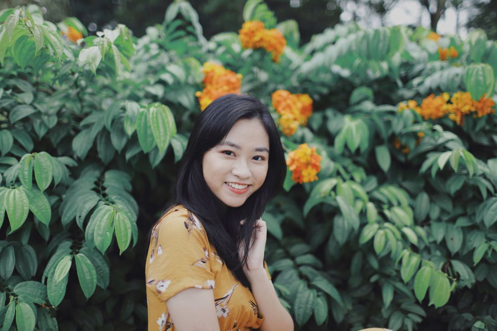 Woman in yellow floral dress standing beside yellow flowers