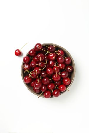 Ripe cherry fruits in a bowl on a light background