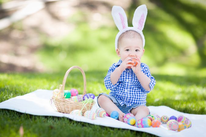 Biracial Baby Boy Outside In Rabbit Ears Playing with Easter Eggs