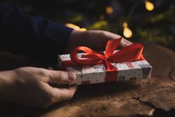 Man holding Christmas gift by wooden table