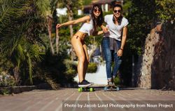 Happy couple riding on skateboards on walkway 0yDgLb