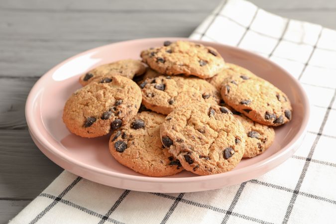Plate with chocolate chip cookies and space for text on wooden table