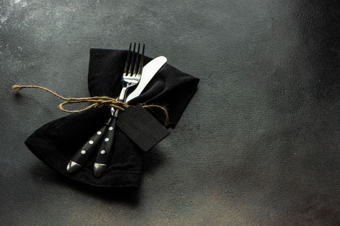 Silverware in matching napkin on counter with copy space and name card