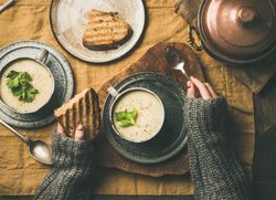Woman with toast, spoon, and celery soup in cup
