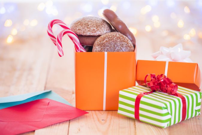 Colorful wrapped presents with cookies and candy on wood table