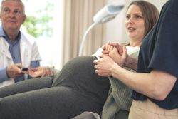 Partner supporting pregnant woman during a medical exam at the clinic.