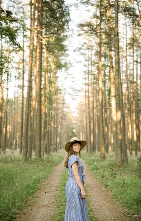 Young woman standing among pine trees