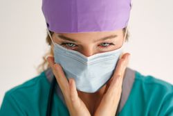 Woman in mask touching face and looking down