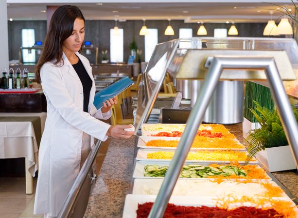 Adult employee checking food quality in canteen