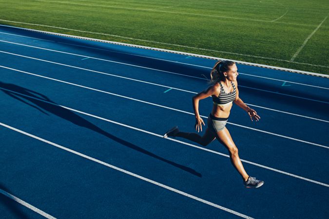 Young woman running on racetrack during training session