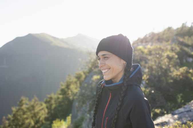 A young woman, mountaineer, sheltered by the cold at the top of a mountain, smile and enjoys the landscape and the moment in nature