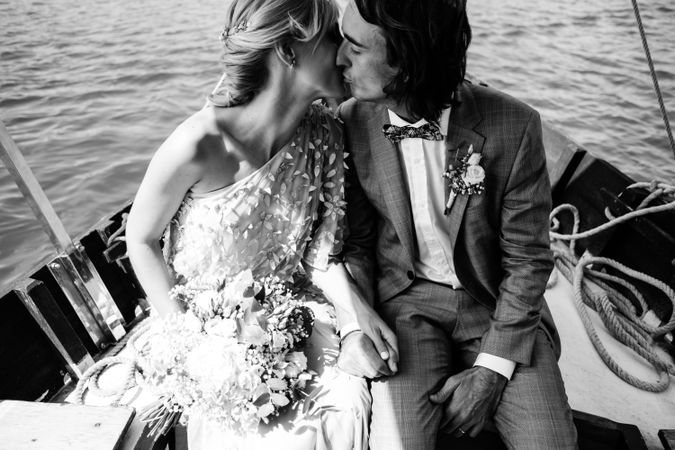 Content newlyweds smiling and holding hands while sitting on boat