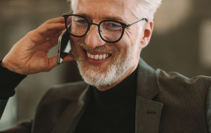 Close up portrait of happy mature businessman talking on phone