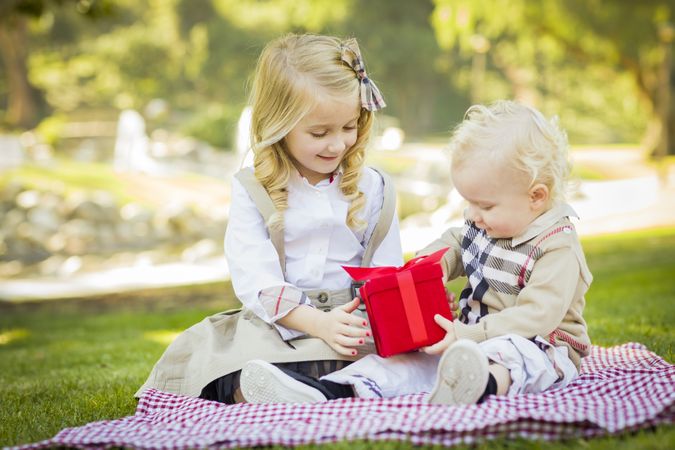 Little Girl Gives Her Baby Brother A Gift at Park.