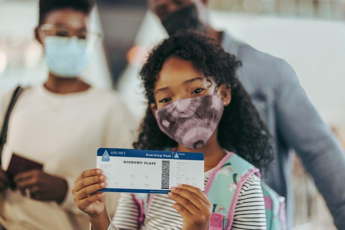 Girl showing boarding pass while at boarding gate with family