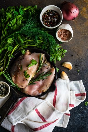 Top view of raw chicken with rosemary sprig on kitchen slab with seasoning with copy space