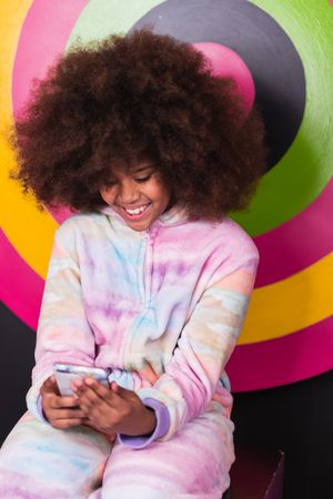 Smiling Black girl using mobile phone in studio