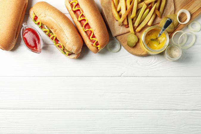 Hot dogs, fries potato and sauces on plain wooden background