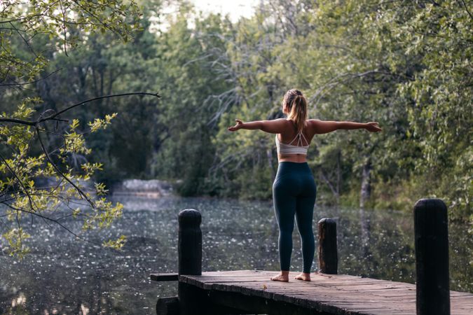 Woman in sportswear doing yoga outdoors near a lake