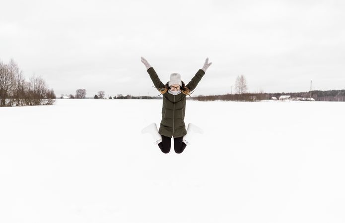 Woman jumping between snow field
