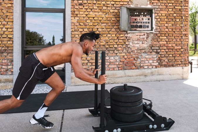 Black guy pulling weights in outdoor gym