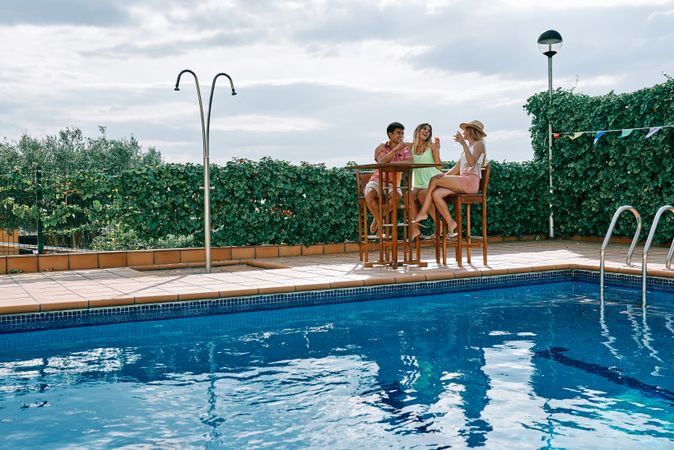 a group of young people having a celebration by the pool on a cloudy summer day