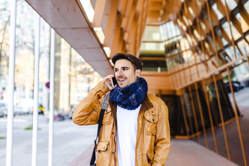 Stylish guy using smartphone outside modern building