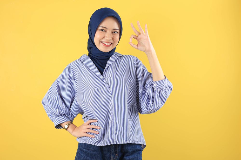 Beautiful Smiling Asian Young Woman in Blue Striped Shirt Showing Okay Gesture