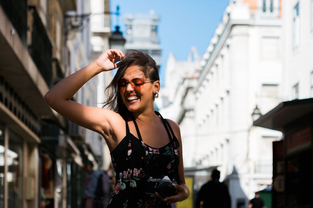 Carefree woman holding a camera on the street
