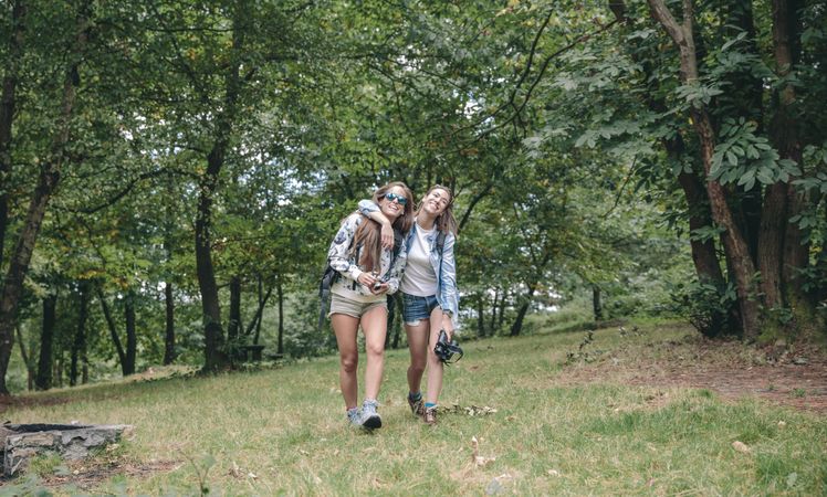 Women friends having fun while walking in forest