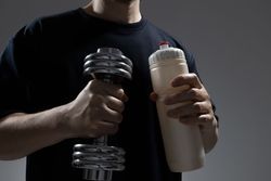Man holding dumbbell and bottle