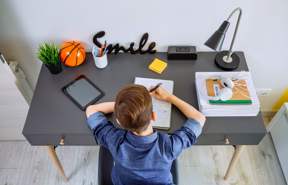 Top view of unrecognizable boy doing homework in his bedroom