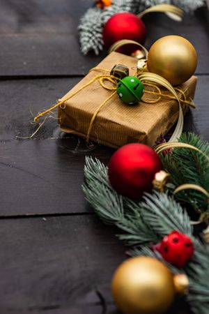 Close up of Christmas gift wrapped in brown paper surrounded by baubles and fir