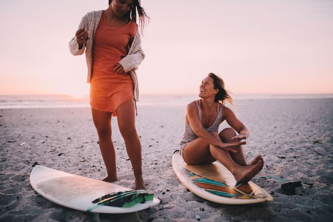 Two happy young women with surfboards at the beach