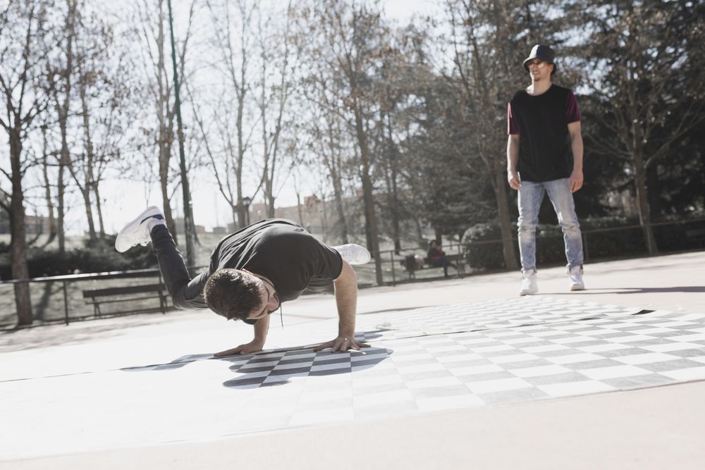 Guy looking at man dancing break dance in park